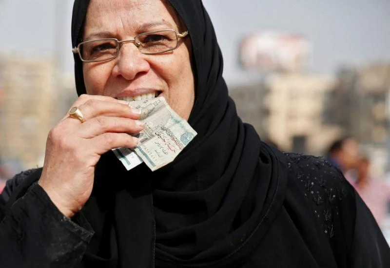 Moody’s estimates that the general government primary deficit has been cut to 1.8 percent of GDP in fiscal year 2017. Above, An Egyptian woman holds her money in her mouth at a market in Cairo. (Reuters)