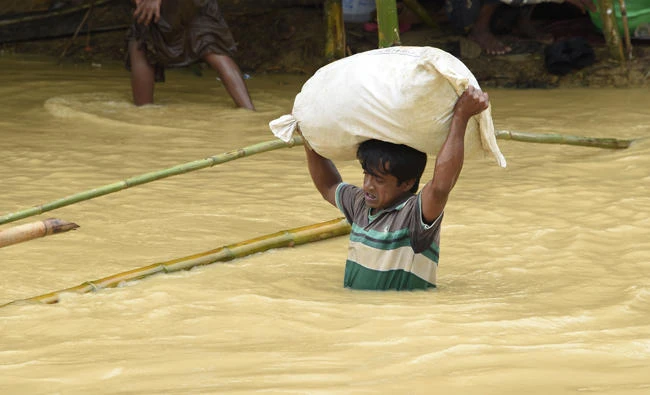 A Rohingya Muslim refugee wades through floodwater at Thyangkhali refugee camp in the Bangladeshi district of Ukhia on on Tuesday. (AFP)