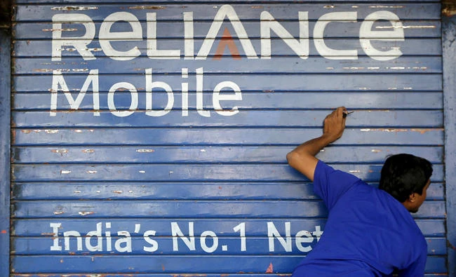 A man opens the shutter of a shop painted with an advertisement of Reliance Communications in Mumbai, India, in this November 3, 2015 file photo. (REUTERS)