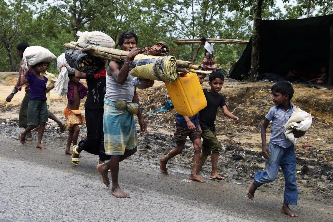 Mujibur Rahman, center, carries his belongings while searching for a place to build a new makeshift shelter for his family at a refugee camp in Bangladesh. AFP