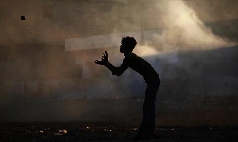 A boy silhouetted against smog while playing cricket in Karachi, Pakistan, in 2011. (File photo by Reuters)