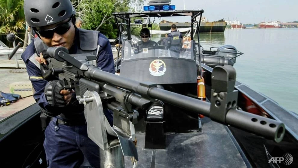 A member of the Malaysian Maritime Enforcement agency poses with a weapon on board a rigid hull fender boat in Malacca, some 148 kilometres (92 miles) southeast of Malaysia's largest city Kuala Lumpur. (AFP)