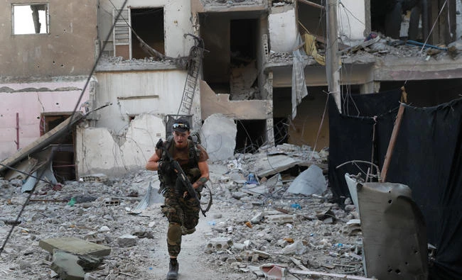 In this file photo, a U.S.-backed Syrian Democratic Forces fighter runs in front of a damaged building as he crosses a street on the front line in Raqqa, Syria. (AP)