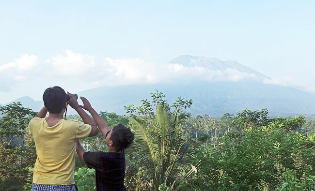 A man observes the Mount Agung with binoculars at a viewing point in Bali, Indonesia, on Wednesday. (AP)
