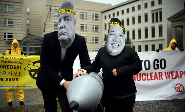 Activists of the non-governmental organization "International Campaign to Abolish Nuclear Weapons (ICAN)" wear masks of US President Donal Trump and North Korea's Kim Jong Un while posing with a mock missile in front of the North Korean embassy in Berlin on September 13, 2017. (AFP / dpa / Britta Pedersen)