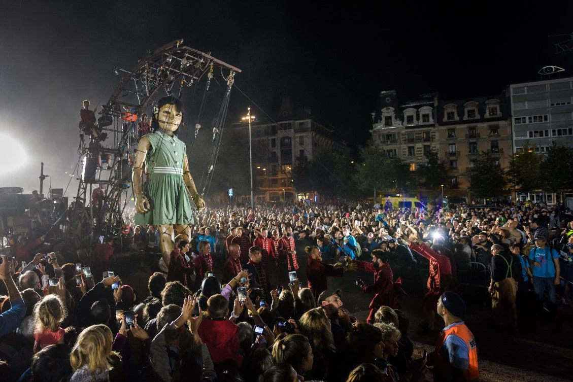 An animated marionette called 'The Little Girl Giant' by French street theatre company Royal de Luxe parades through the streets of Carouge during their 'The Saga of the Giants' performance on September 29, 2017 in Geneva. The Royal de Luxe Company are to perform in Geneva until October 1, 2017. - / AFP / Fabrice COFFRINI