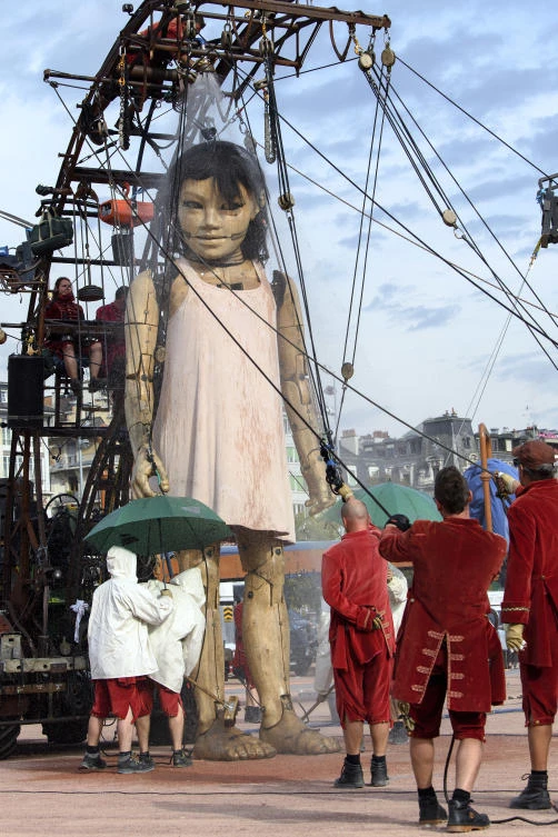 A giant puppet, takes a shower as it parades through the spectators during the "The Saga of the Giants" street theater, in Geneva, Switzerland, Saturday, Sept. 30, 2017. The giants of the Royal de Luxe Company guest in Geneva on the theme "The Knight of the Lost Time". (Martial Trezzini/Keystone via AP)