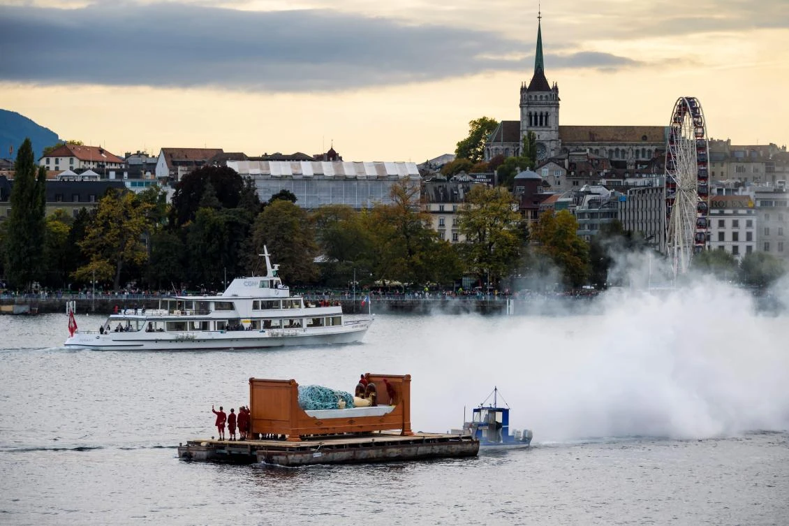 A 7,30 meters high giant animated puppet representing a grandmother created by French street theatre company Royal de Luxe, is seen on a bed on Geneva Lake during the last act of "The Saga of the Giants" a three days street performance gathering hundred thousand spectators, October 1, 2017, in Geneva. - / AFP / Fabrice COFFRINI