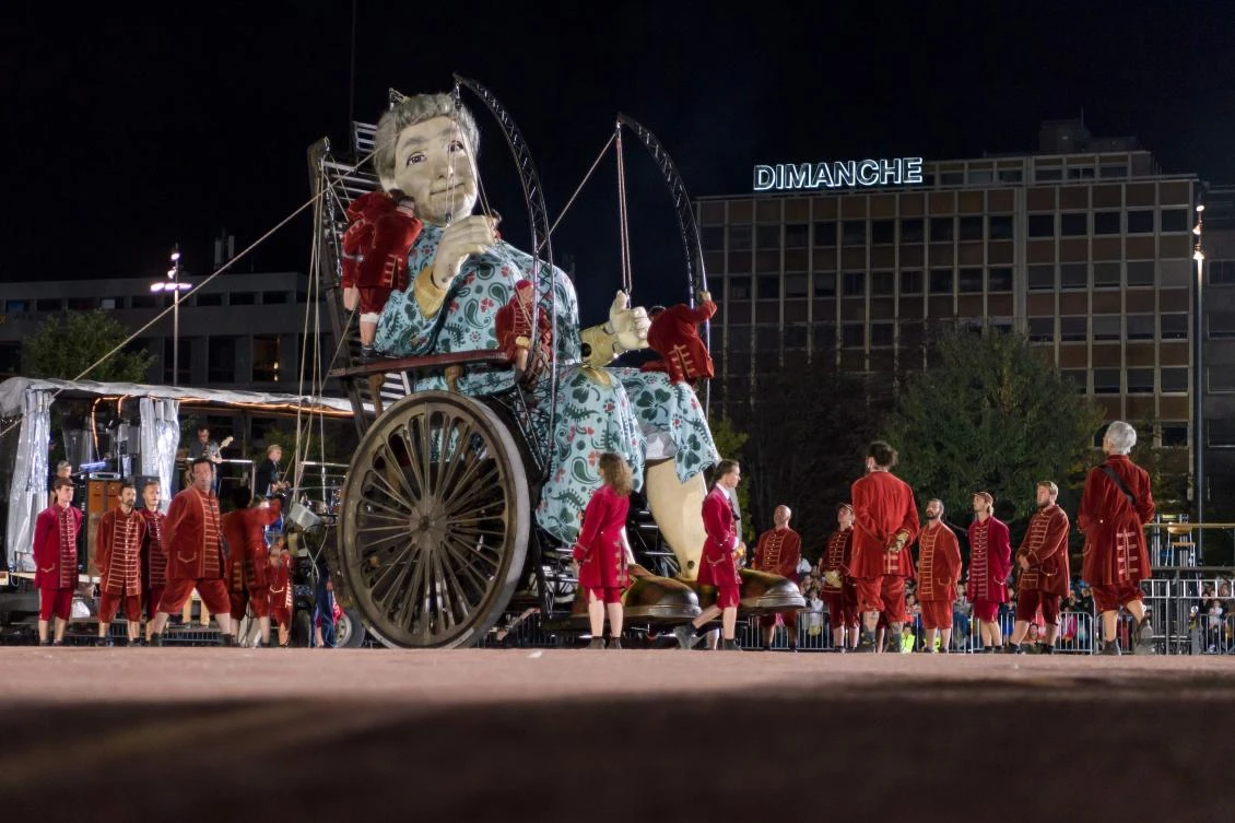 So-called 'Lilliputians' work around an animated marionette called 'The Grandmother Giant' by French street theatre company Royal de Luxe as they parade through the streets of Carouge during their 'The Saga of the Giants' performance on September 29, 2017 in Geneva. The Royal de Luxe Company are to perform in Geneva until October 1, 2017. - / AFP / Fabrice COFFRINI