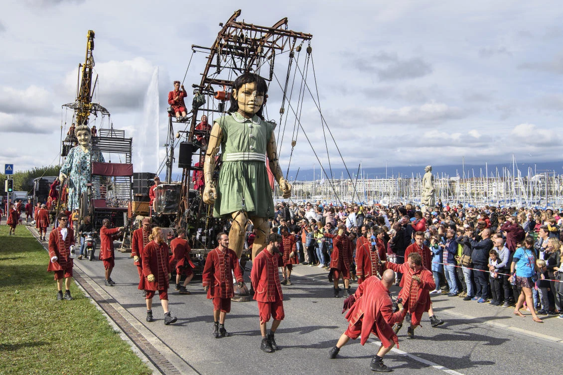 Two giants, a grandmother giant puppet, behind, and a little giant puppet, in front, parade next to the famous water fountain "Le Jet d'Eau" during the "The Saga of the Giants" street theater, in Geneva, Switzerland, Sunday, Oct. 1, 2017. (Martial Trezzini/Keystone via AP)