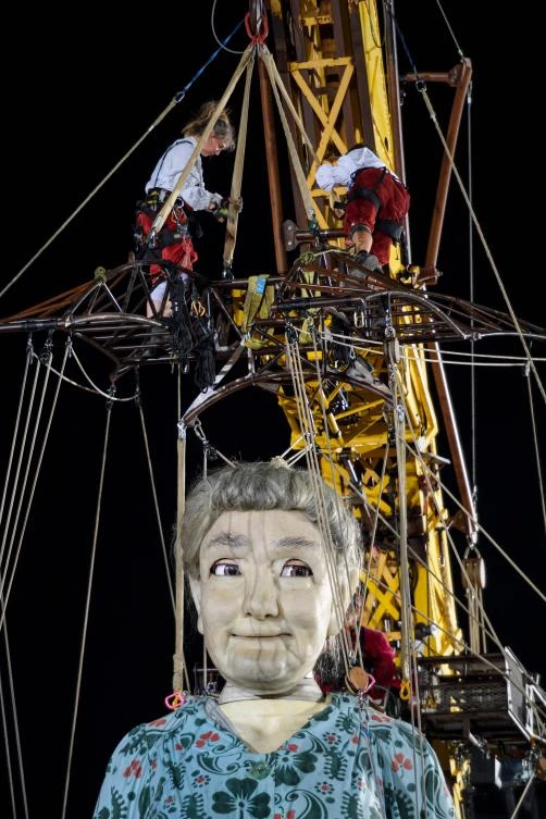 So-called 'Lilliputians' work around an animated marionette called 'The Grandmother Giant' by French street theatre company Royal de Luxe as they parade through the streets of Carouge during their 'The Saga of the Giants' performance on September 29, 2017 in Geneva. The Royal de Luxe Company are to perform in Geneva until October 1, 2017. - / AFP / Fabrice COFFRINI