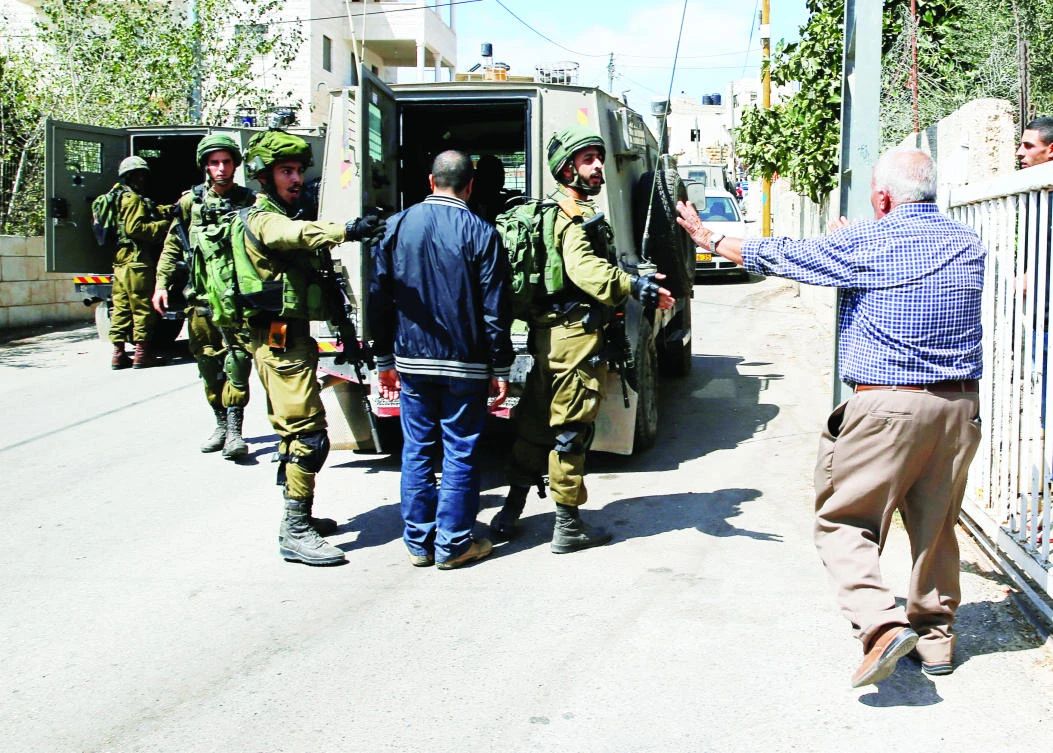 A Palestinian man argues with Israeli soldiers as they arrest the brother of Nimr Jamal near Ramallah on Tuesday. Jamal was earlier shot dead by Israelis in an illegal settlement outside Jerusalem. (Reuters)