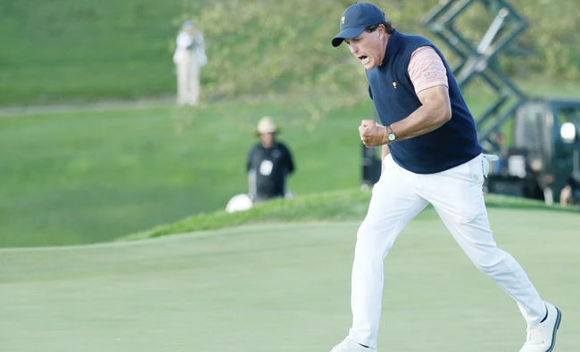 Phil Mickelson of the US Team celebrates on the 18th green after he and teammate Kevin Kisner defeated International Team's Australians Marc Leishman and Jason Day 1 up during the fourball matches of the Presidents Cup at Liberty National Golf Club on Friday in Jersey City, New Jersey. (AFP)