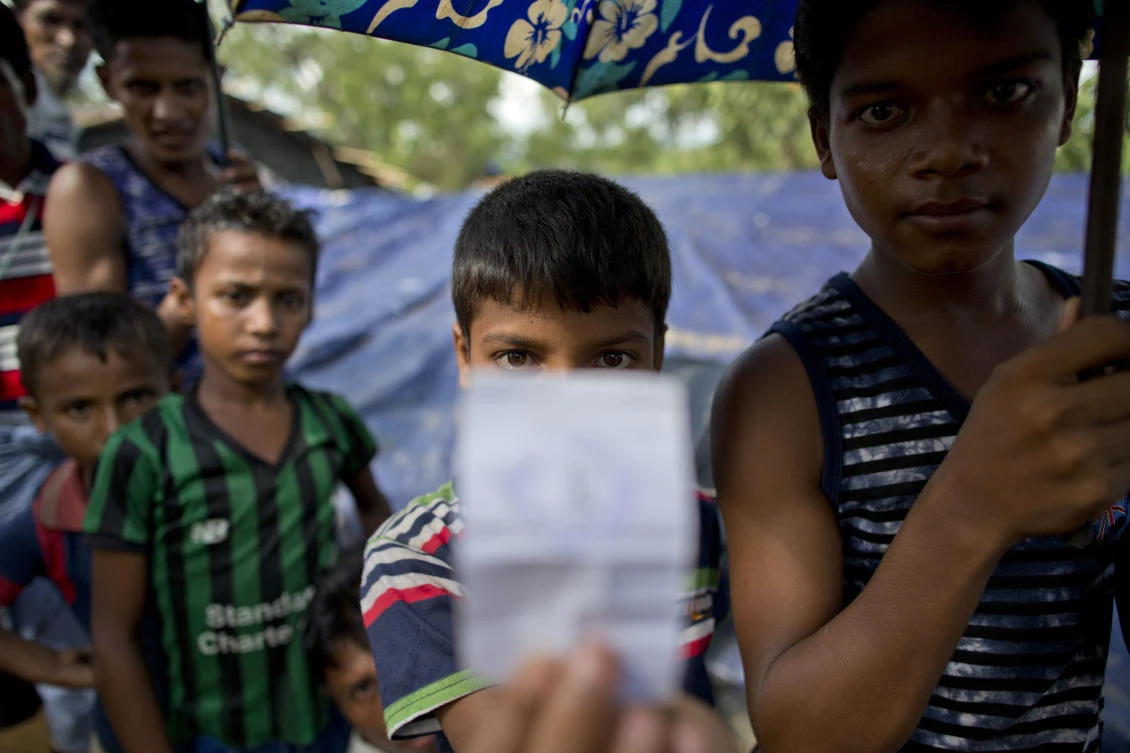 A newly arrived Rohingya boy stands in line, and displays a food rations coupon while waiting to receive dry food in Kutupalong, Bangladesh, Saturday, Sept. 30, 2017. Some five weeks after the mass exodus of Rohingya from Myanmar began, the U.N. says the total number of arrivals in Bangladesh has now topped 501,000, and refugees are still arriving.(AP Photo/Gemunu Amarasinghe)