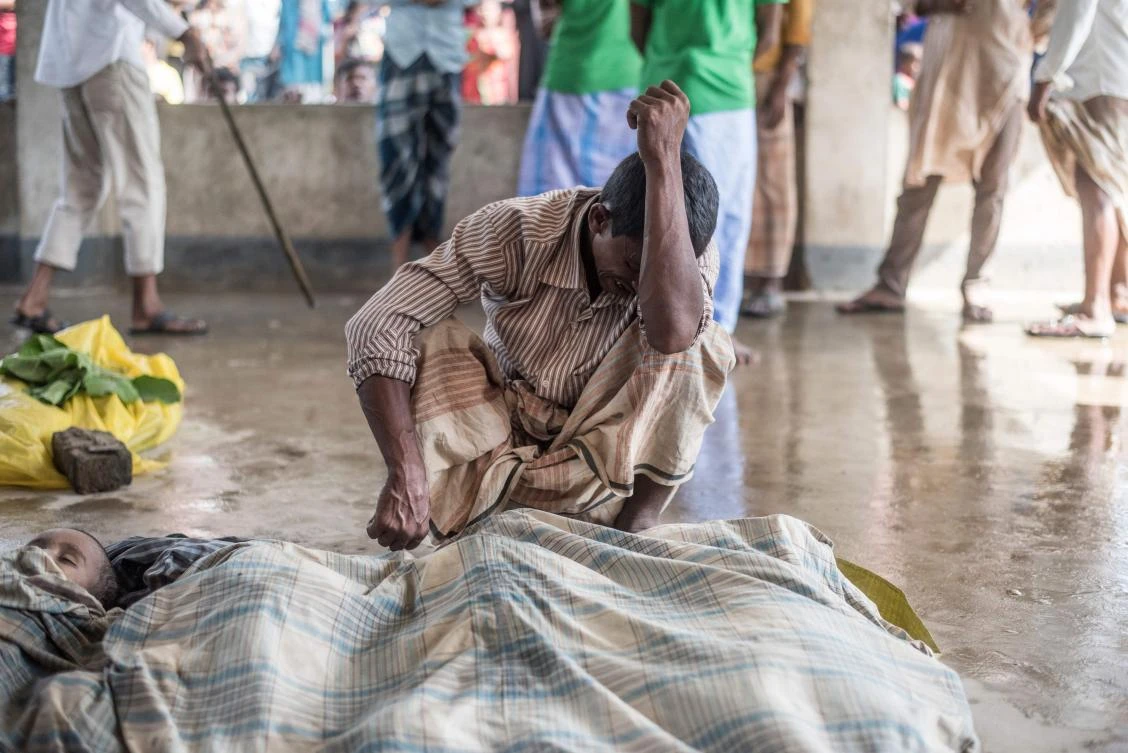 A Rohingya Muslim refugee mourns beside the bodies of his three children at a school near Inani beach in Cox’s Bazar district on September 29, 2017. (File photo by AFP)