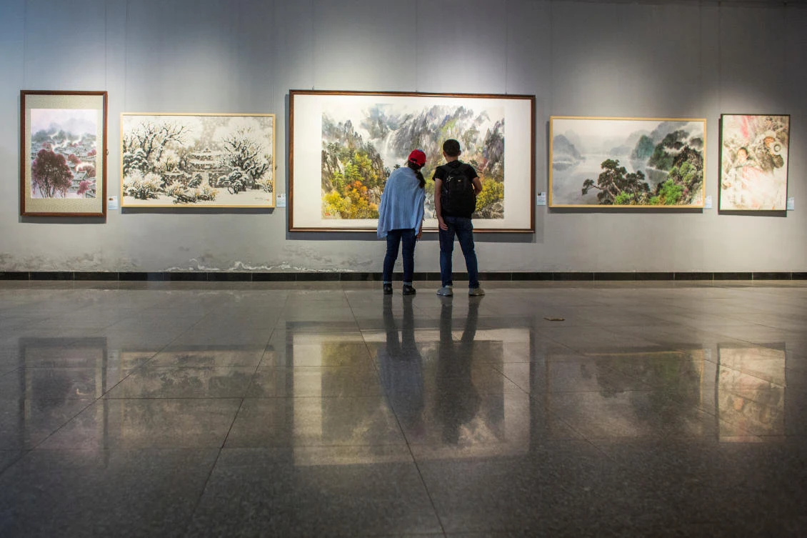 Visitors look at works by North Korean artists at the Mansudae Art Museum in the 798 art district in Beijing, China, September 20, 2017. Picture taken September 20, 2017. To match Insight NORTHKOREA-CHINA/ART REUTERS/Thomas Peter NO ARCHIVES NO RESALES