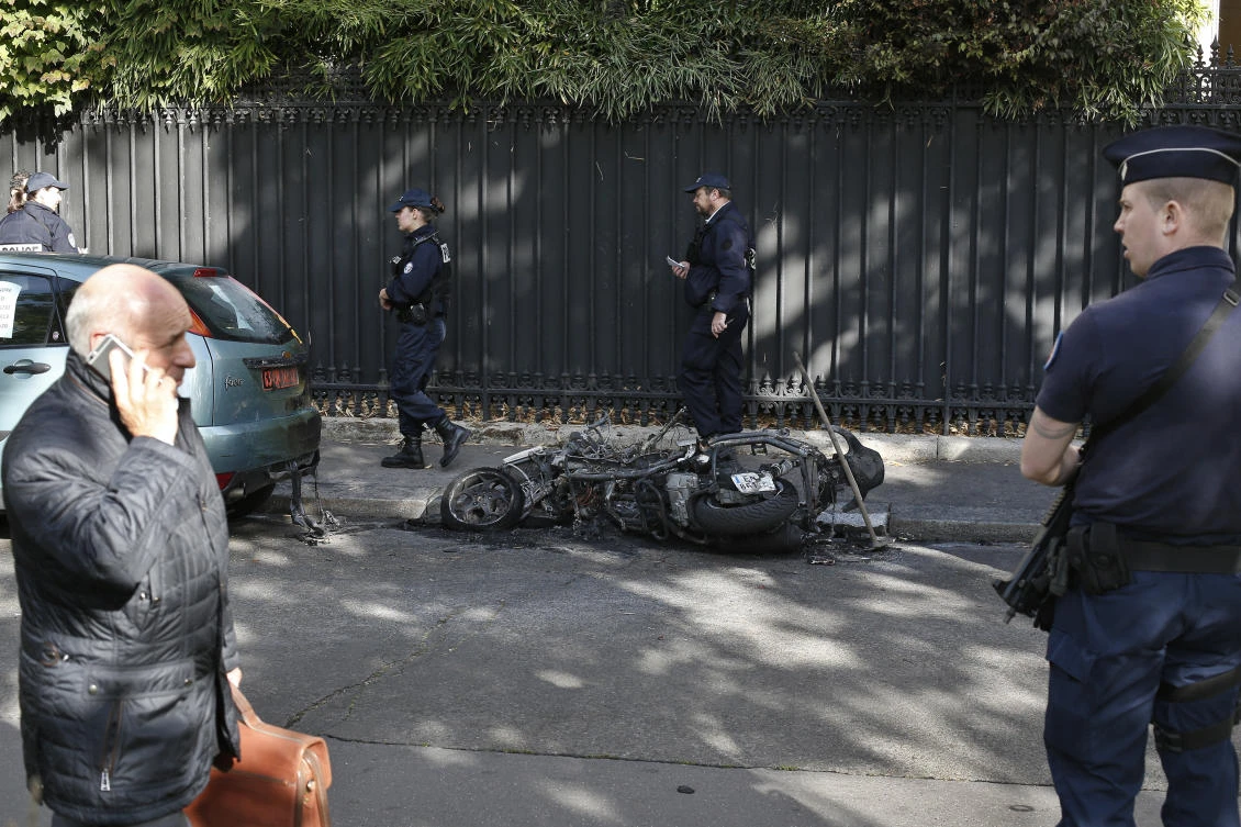 Police officers stand next to a burnt scooter outside the office of Jordan’s military attache in Paris, Wednesday, October 4, 2017. (AP)