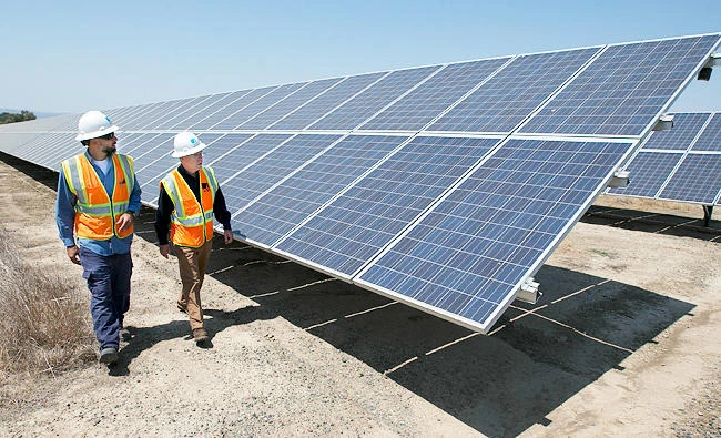 In this Aug. 17, 2017 photo, solar tech Joshua Valdez, left, and senior plant manager Tim Wisdom walk past solar panels at a Pacific Gas and Electric Solar Plant, in Dixon, Calif. (AP)