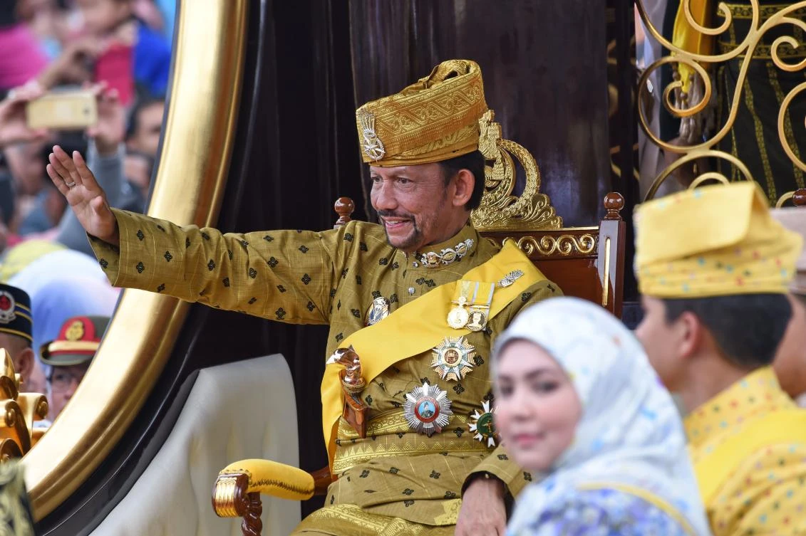 Brunei’s Sultan Hassanal Bolkiah, left, waves from the royal chariot during a procession to mark his golden jubilee of accession to the throne. (AFP)