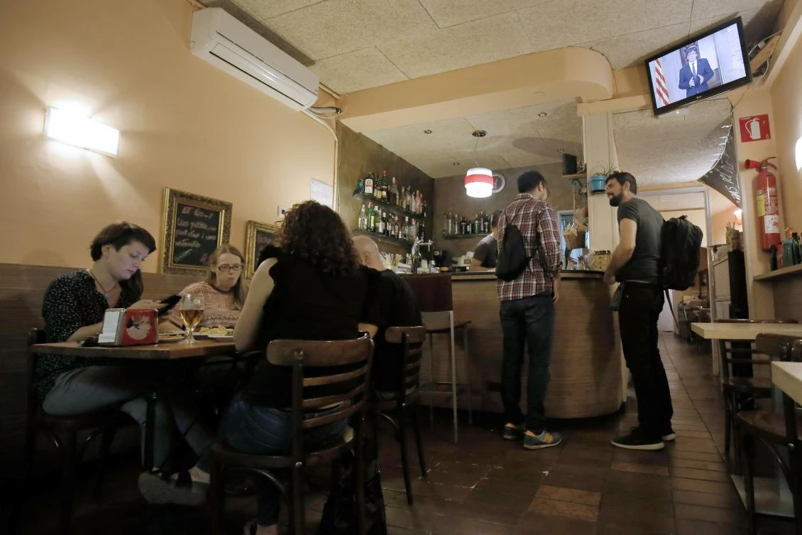 Customers watch a television broadcast of a statement being delivered by Catalan president Carles Puigdemont. Catalan leaders said they could unilaterally declare independence as early as Monday. (AFP)