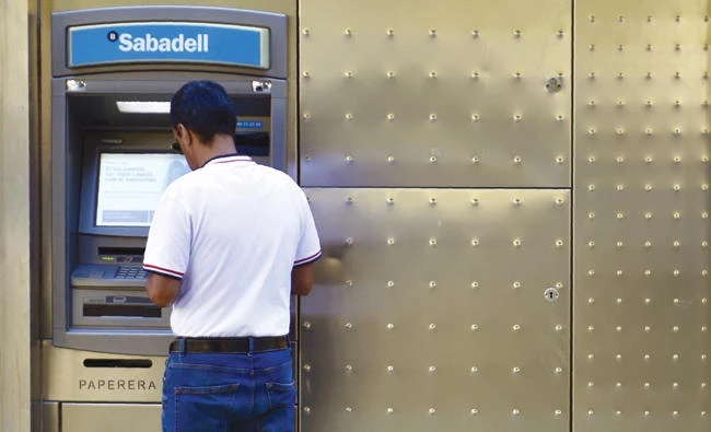 A man withdraws cash from an ATM in Barcelona. Spanish banking stocks have suffered amid a crisis between Madrid and the separatist leaders of Catalonia. (AFP)