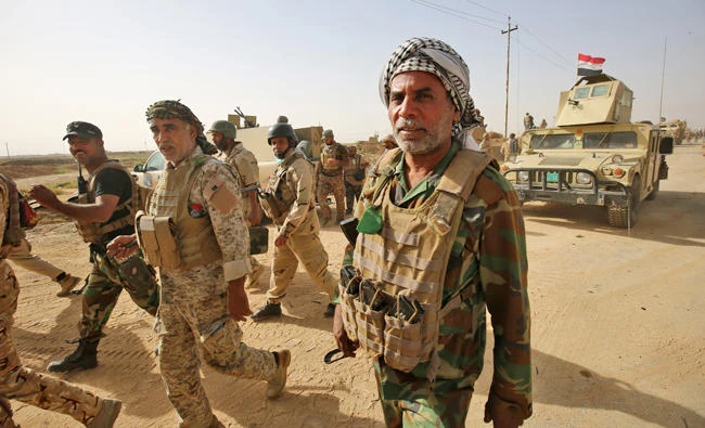 Fighters from the Hashed al-Shaabi (Popular Mobilisation units), backing the Iraqi forces, advance through Hawija on Thursday, after retaking the city from Daesh group fighters. Iraqi forces retook one of the Daesh group's last two enclaves in the country on October 5, overrunning the longtime insurgent bastion of Hawija after a two-week offensive. (AFP)