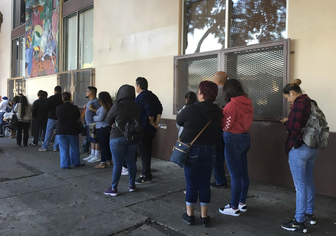 Above, people wait in line at CHIRLA (Coalition for Humane Immigrant Rights Los Angeles) for help with immigration paperwork, including renewing work permits. (AP)