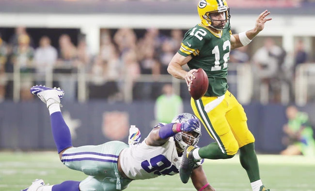 Green Bay Packers quarterback Aaron Rodgers (12) runs with the ball for a first down in the fourth quarter against Dallas Cowboys defensive tackle David Irving (95) at AT&T Stadium on Sunday. (USA TODAY Sports)
