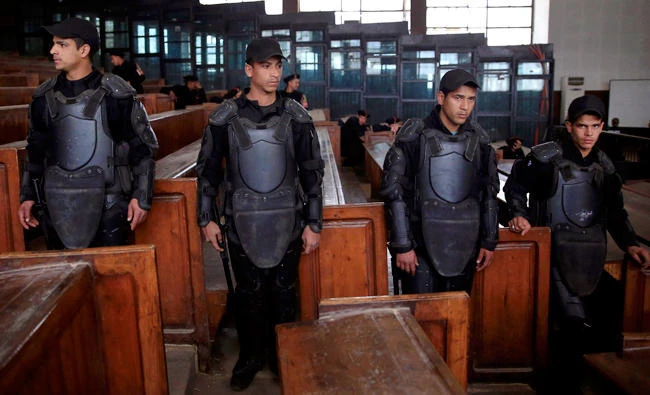 In this file photo, Egyptian policemen stand guard in front of the courtroom defendant's cage during a verdict hearing on a case that stems from clashes near the Muslim Brotherhood's headquarters in Cairo, Egypt, on June 30, 2013. (AP)