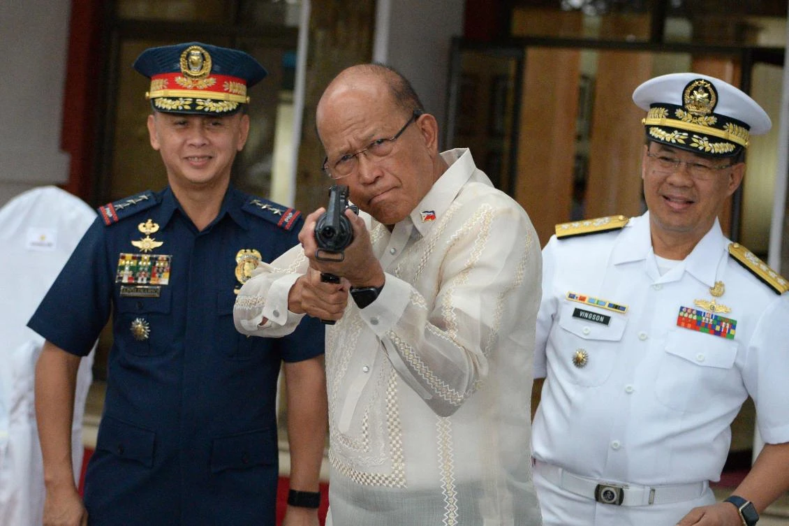 Philippine Defense Secretary Delfin Lorenzana, center, tries a CQ-A5b (M4) rifle donated by the Chinese government during the ceremony at the military headquarters in Manila on October 5, 2017. (File photo by AFP)