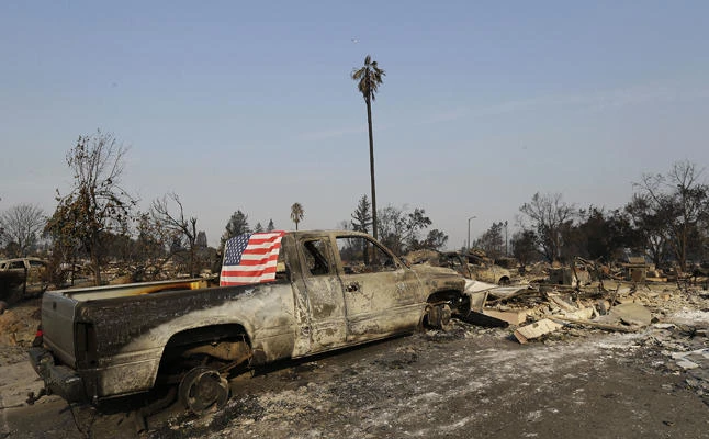 A flag is draped on the back of a truck destroyed by fires in Santa Rosa, California, on Wednesday, Oct. 11, 2017. (AP Photo/Jeff Chiu)