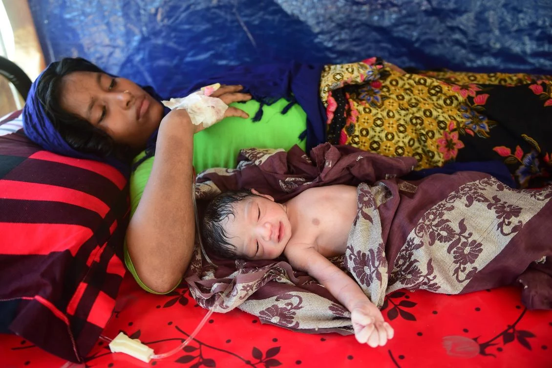 This picture taken on October 11, 2017 shows pregnant Rohingya woman Hasina Aktar lying in bed with her newborn baby Mohammed Jubayed at a medical centre in Kutupalong refugee camp. Mohammed Jubayed came into the world shortly after midday in a baking hot military tent amid the chaos of a vast refugee camp in Bangladesh, now home to nearly a million Rohingya. Just an hour earlier, a cycle rickshaw had pulled up carrying his young mother Hasina Aktar clutching her stomach and moaning in pain in the throes of labour with her second child. The United Nations says pregnant or breast-feeding women account for one in 10 of the estimated 520,000 Rohingya who have arrived in Bangladesh over the last six weeks after fleeing an upsurge in violence in neighbouring Myanmar. (AFP)