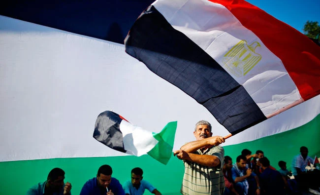 A Palestinian man waves the flags of Egypt and Palestine as people gather in Gaza City to celebrate after rival Palestinian factions Hamas and Fatah reached an agreement on ending a decade-long split following talks mediated by Egypt on Thursday, October 12, 2017. (AFP / MOHAMMED ABED)