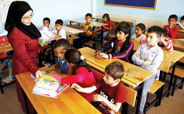 A Syrian refugee teacher in this file photo distributes books to her refugee students in the Karapurcek district of Ankara. (Reuters)