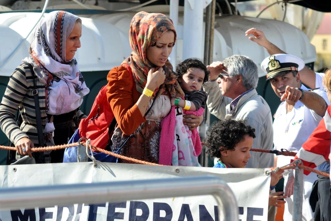 A woman holds a baby as she disembarks from rescue ship Aquarius run by NGO "SOS Mediterranée" after a rescue operation at sea on Friday in Palermo, Sicily. (AFP)