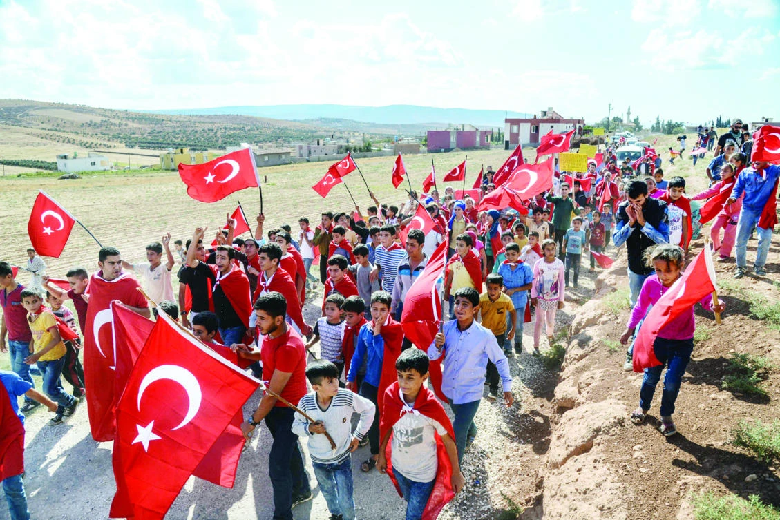 People wave Turkish flags during a demonstration in support of the Turkish Army’s Idlib operation near Reyhanli, Hatay, on the Turkey-Syria border. (AFP)
