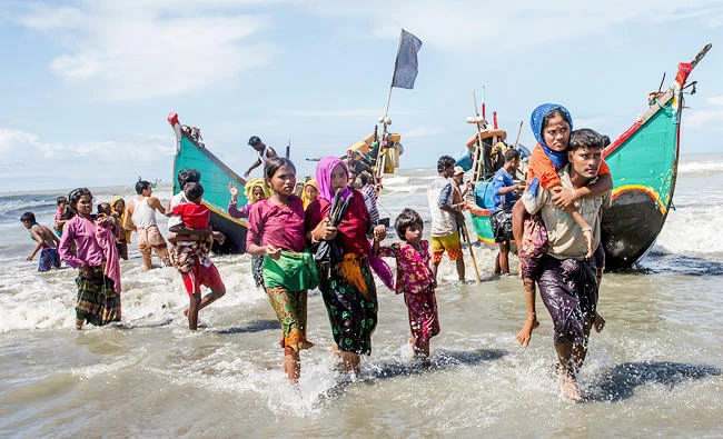 In this Sept. 14, 2017 photo, Rohingya Muslims walk towards shore after arriving on a boat from Myanmar to Bangladesh in Shah Porir Dwip, Bangladesh. (AP)
