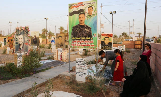Iraqis visit the grave of a relative, who was killed during battles with Daesh, at a graveyard in the Iraqi town of Dhuluiyah on Wednesday. (AFP)