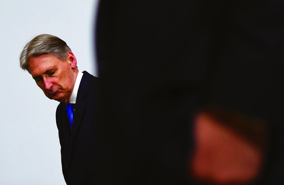 British Finance Minister Philip Hammond tries to find his place to stand on the stage for the G-20 finance ministers group photo at the IMF headquarters in Washington last week. He now finds himselfat the center of a fraught debate over Brexit. (AFP)