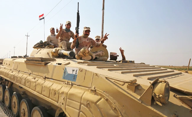 Iraqi forces flash the sign for victory as they drive towards Kurdish peshmerga positions on Sundy, on the southern outskirts of Kirkuk. (AFP)