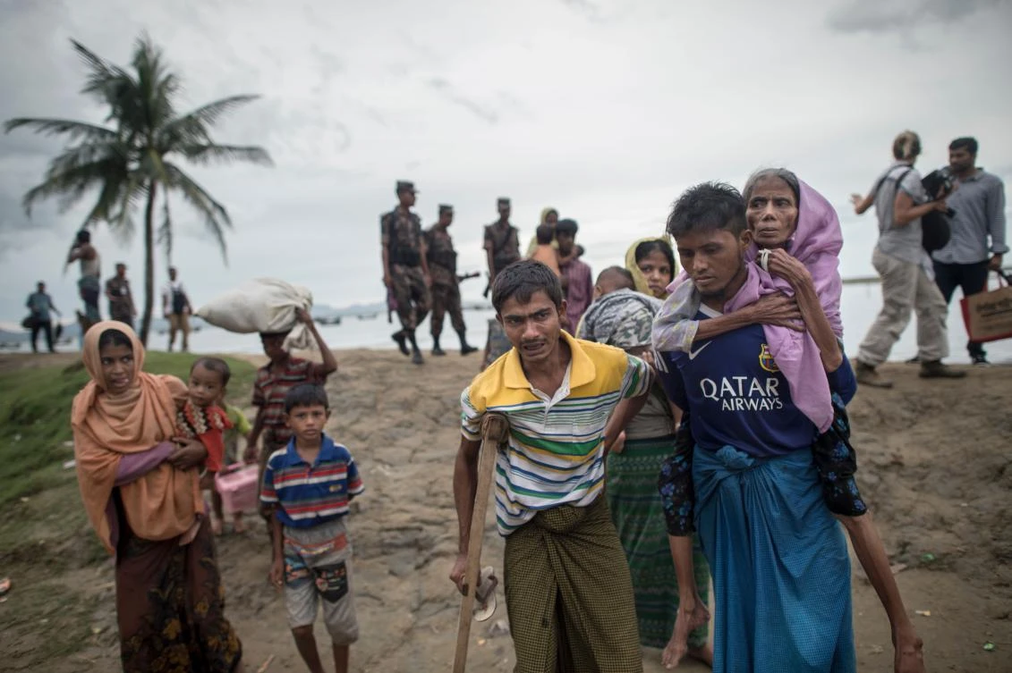 Rohingya Muslim refugees walk in front of Bangladeshi coastguards after crossing the border from Myanmar at the Bangladeshi shores of the Naf river in Teknaf on October 5, 2017. More than half a million Rohingya have fled ethnic bloodshed in Rakhine since late August, many by boat across the Naf River which divides Myanmar and Bangladesh. (AFP)