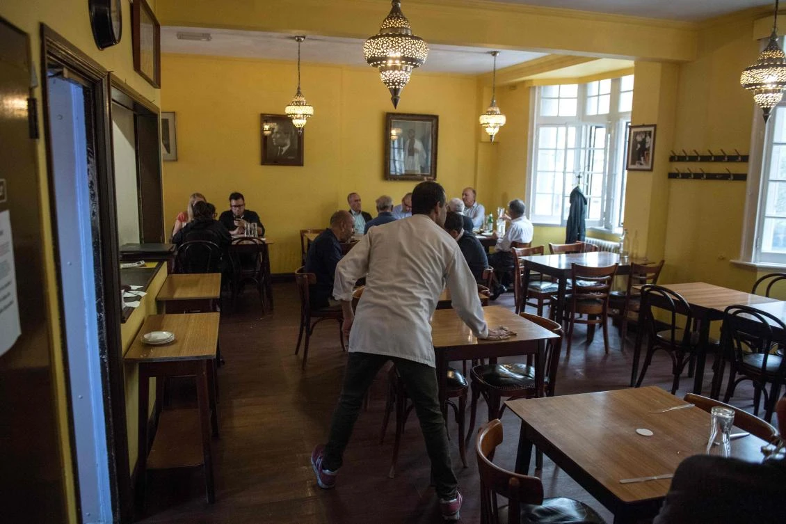 Staff clean tables as people eat lunch inside the India Club restaurant in London on October 16, 2017. (AFP)