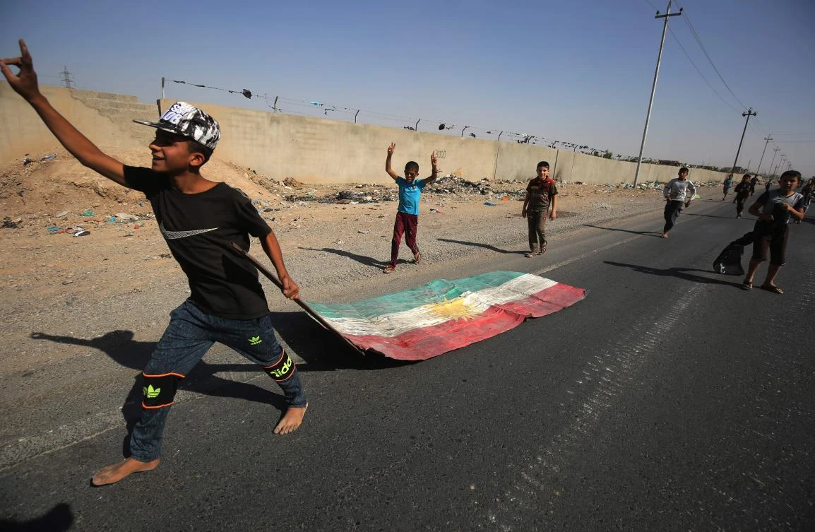 An Iraqi boy drags a Kurdish flag as Iraqi forces advance toward the center of Kirkuk during an operation against Kurdish fighters on Oct. 16, 2017. (AFP/Ahmad Al-Rubaye)