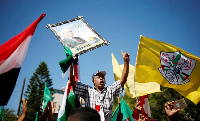 A man holds a picture of Palestinian President Mahmoud Abbas during celebrations after Hamas said it reached a deal with Palestinian rival Fatah, in Gaza City on October 12, 2017. (Reuters)