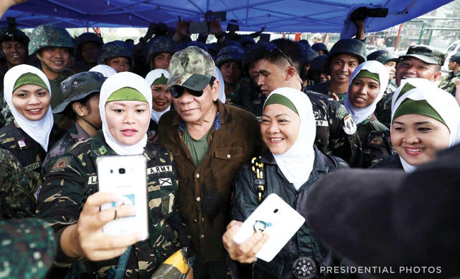 Philippine President Rodrigo Duterte poses with female soldiers during his visit at Bangolo town in Marawi city on Tuesday. (Reuters)