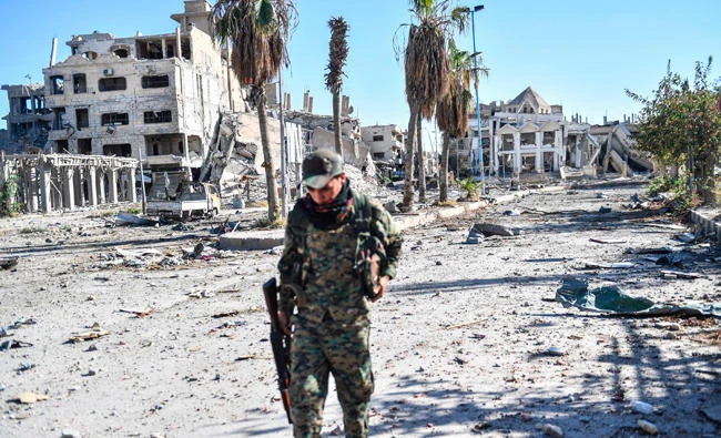 A member of the Syrian Democratic Forces walks through a heavily damaged a street leading to a church in Raqqa on Wednesday. (AFP)