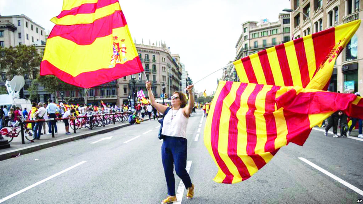 A woman waves flags of Catalonia and Spain as people celebrate a holiday known as ‘Dia de la Hispanidad’ or Spain’s National Day in Barcelona, in this Oct. 12 photo. (AP)