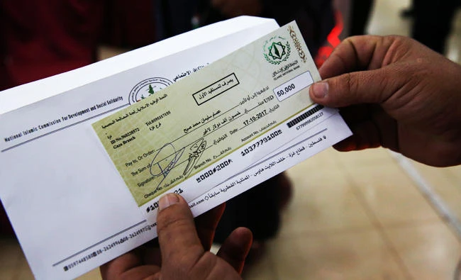 In this Oct. 17, 2017 photo, a relative shows a check for $50,000 to Esam Subeh's family during a social reconciliation ceremony in Beit Lahiya City, Gaza Strip. (AP)