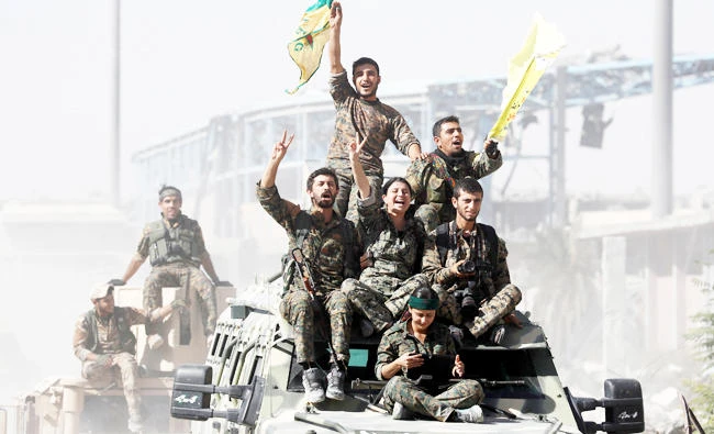 Syrian Democratic Forces (SDF) fighters ride atop military vehicles as they celebrate victory in Raqqa, Syria, in this October 17, 2017 photo. (REUTERS)