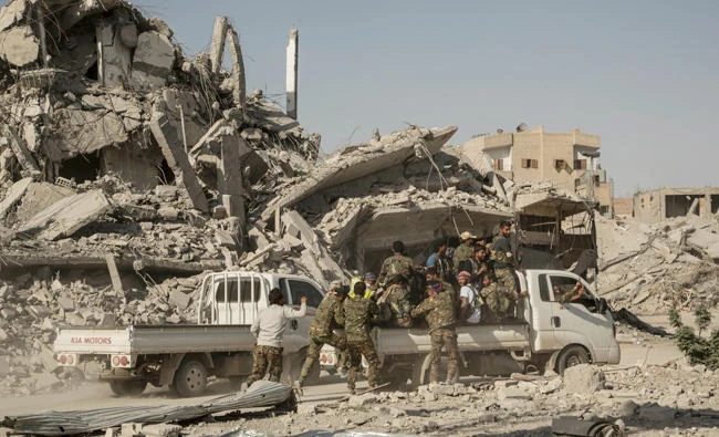 Members of the US-backed Syrian Democratic Forces gather near the main traffic circle in Raqqa on Friday. (AP)